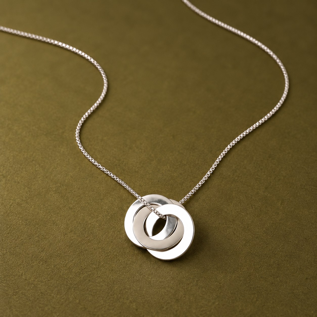 Dije de círculos entrelazados en plata sobre cadena